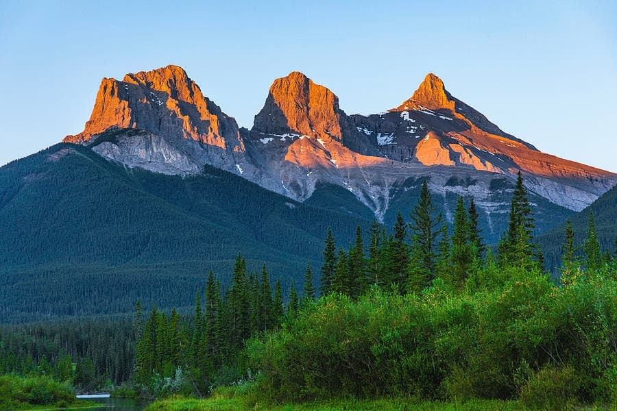Sunlit mountain peaks and forest near alpine trail for hiking