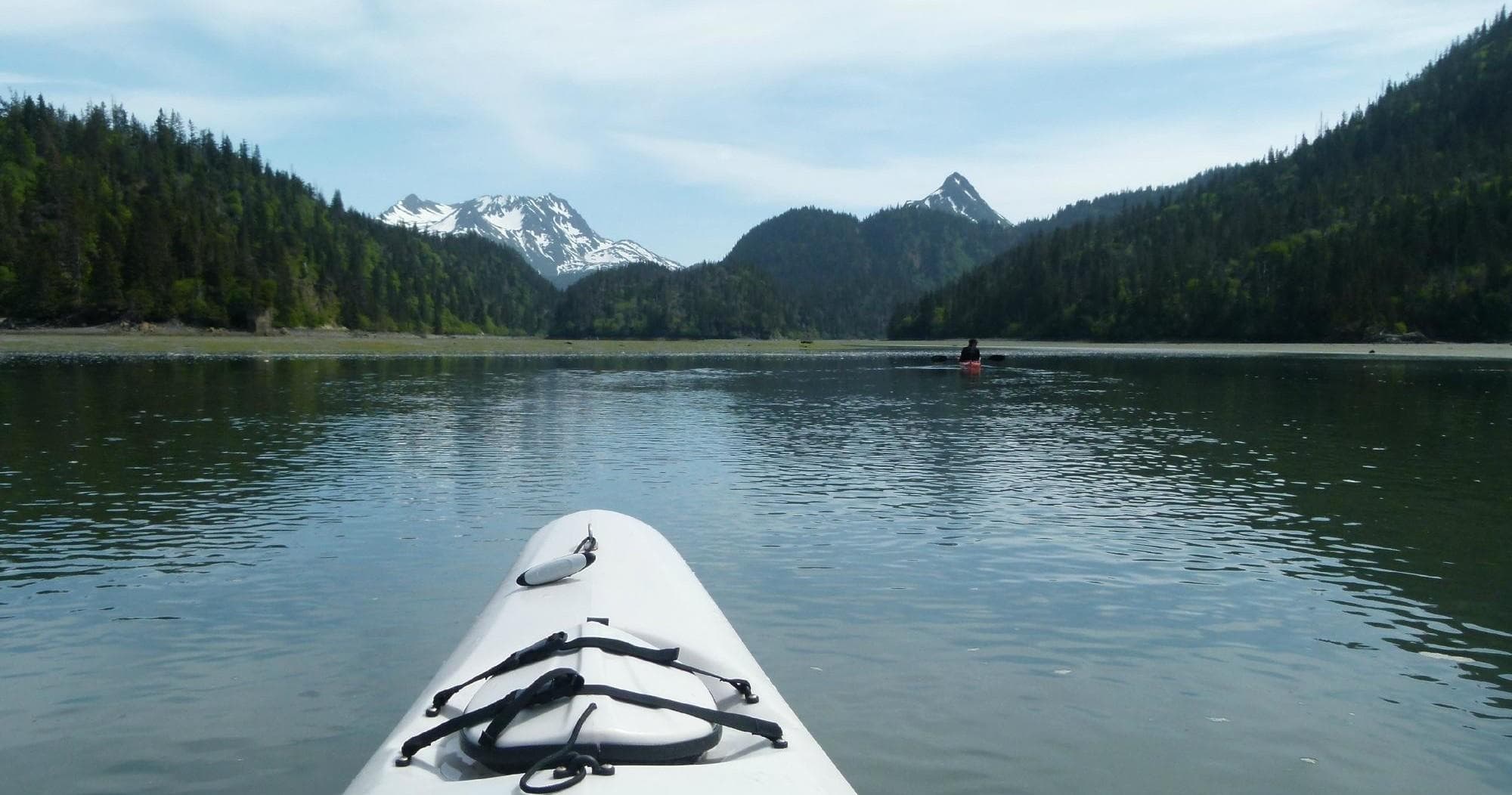 Kayak bow on alpine lake with distant snow-capped peaks
