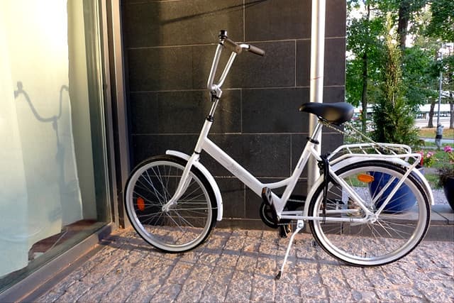 City bicycle parked on stone sidewalk outside urban building