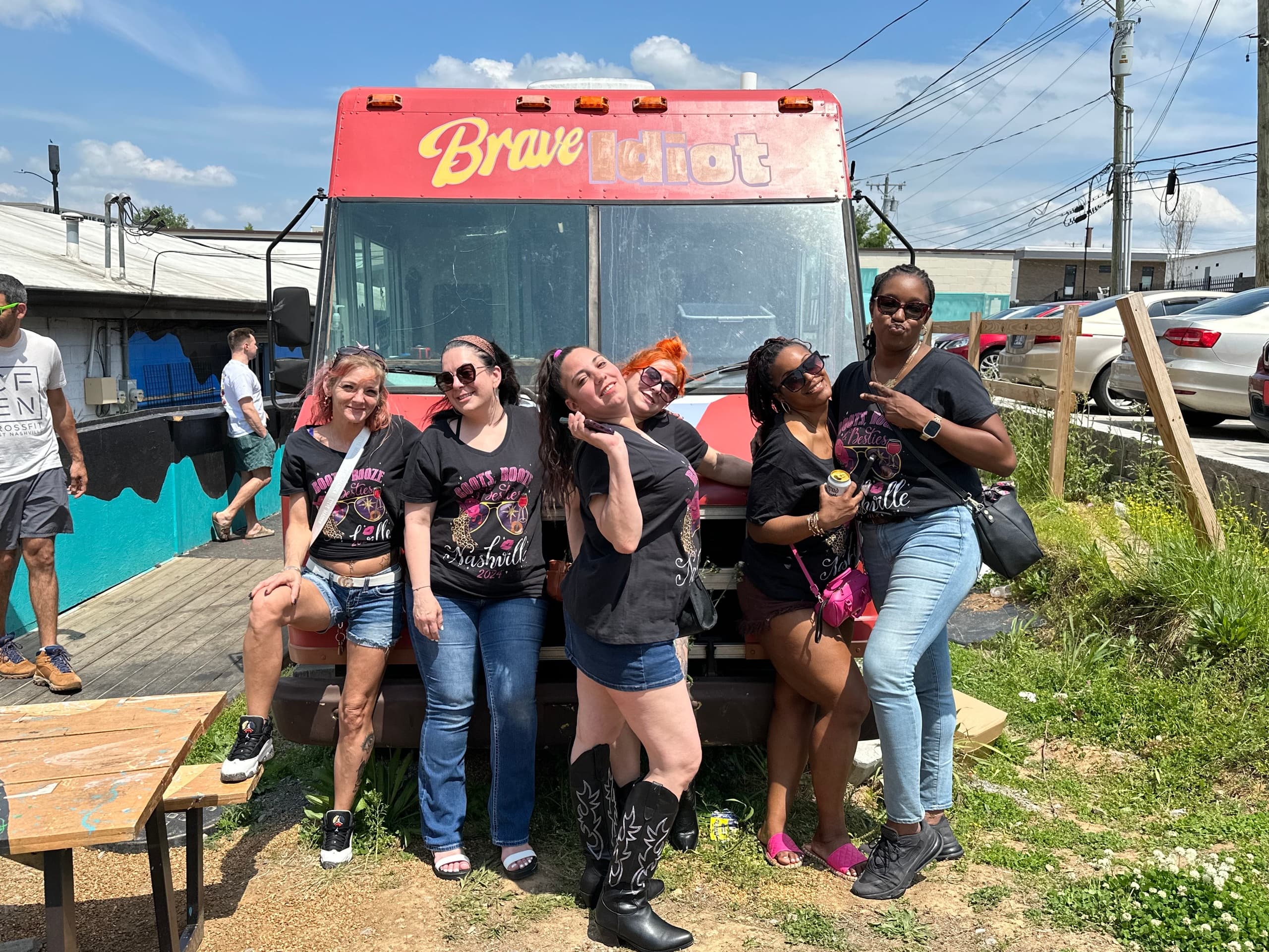Friends posing with sandwiches at outdoor food truck, sunny picnic vibe