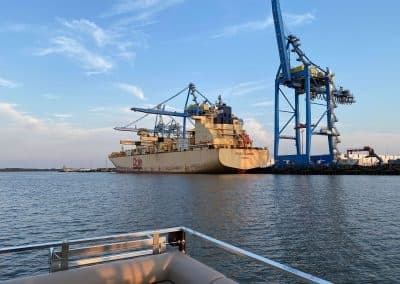 Cargo ship moored at industrial harbor with cranes on skyline