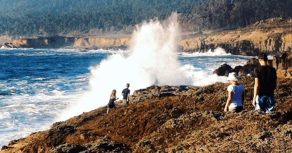Spectators watching waves crash on rocky Pacific coast bluff