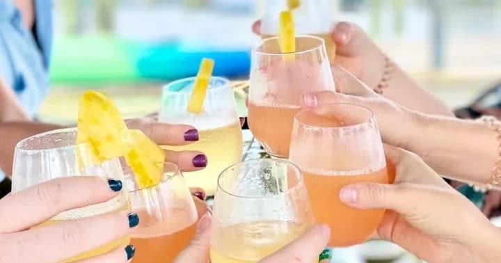 Group toasting tropical cocktails on yacht deck during day