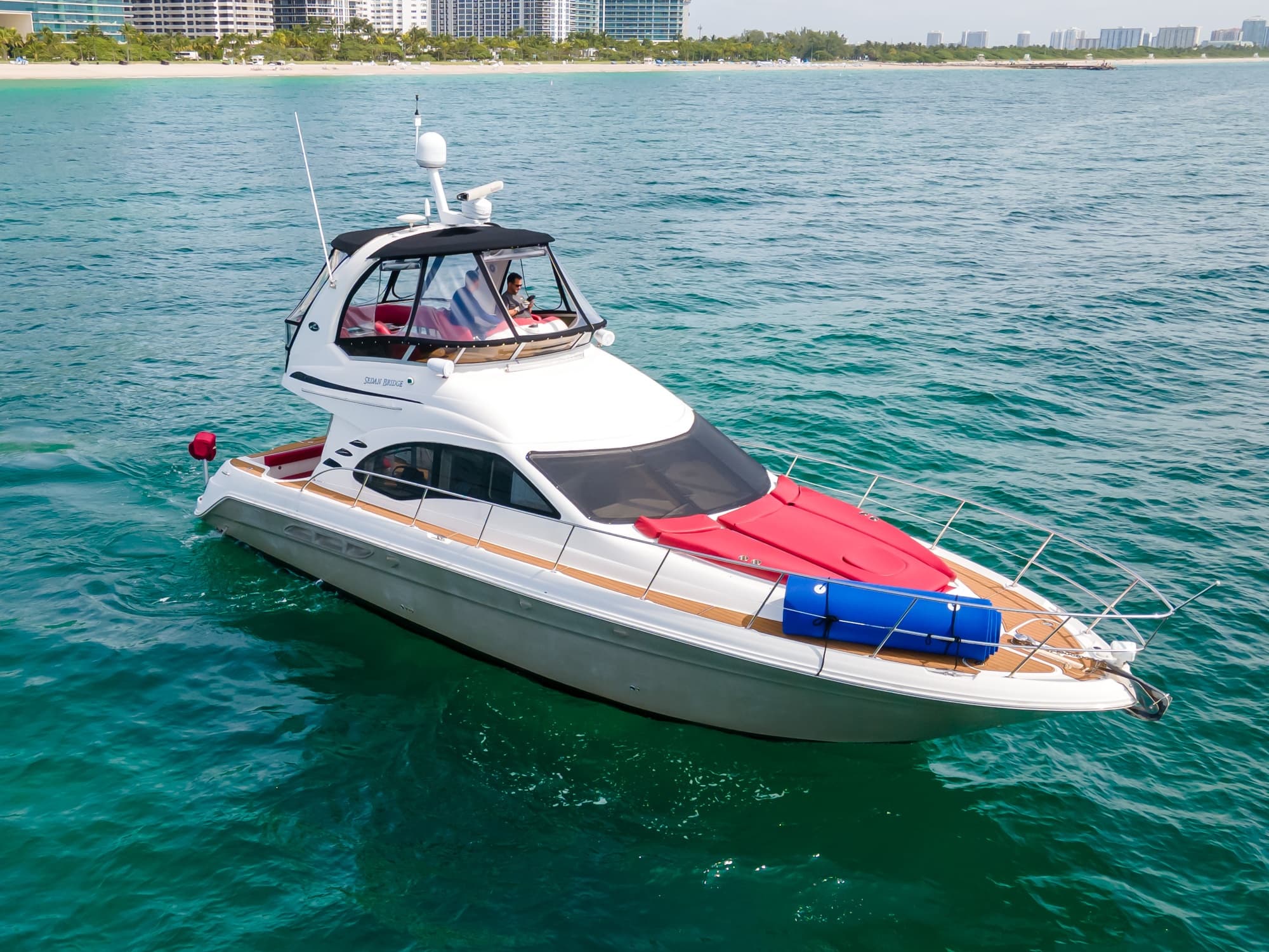 Sporty motor yacht cruising clear ocean waters with colorful fenders