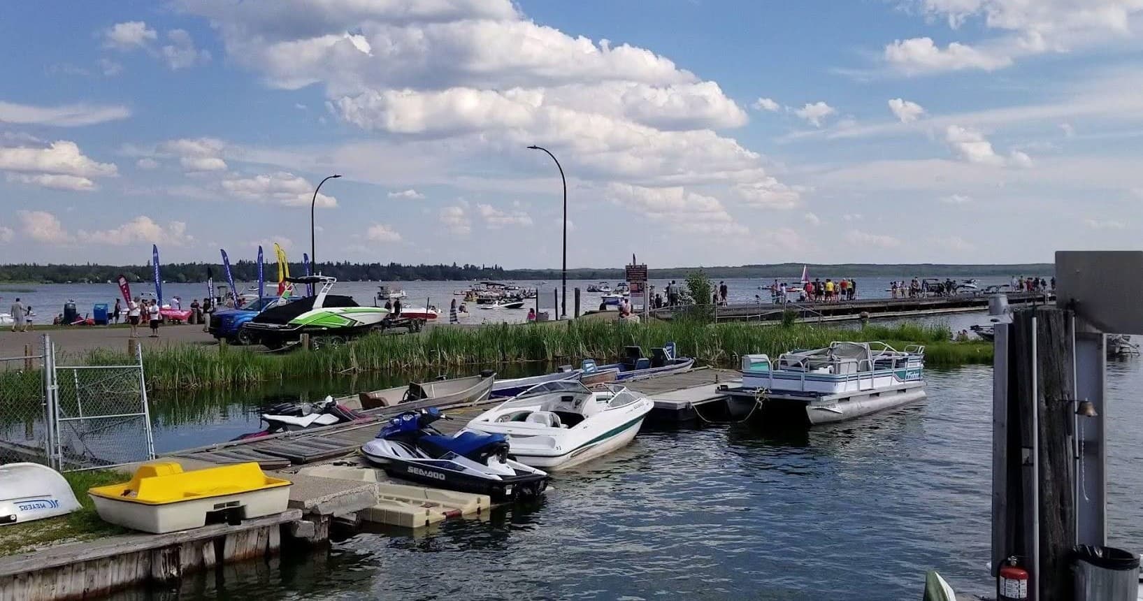 Small pleasure boats tied at lakeside marina with visitors