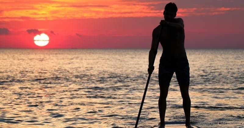 Standup paddler silhouetted at Scottish sunset on calm sea