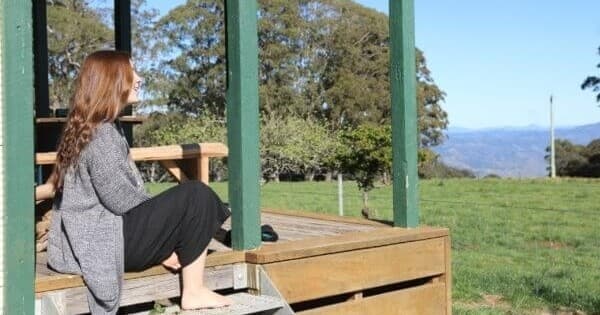 Guest relaxing on farmhouse porch overlooking rolling valley