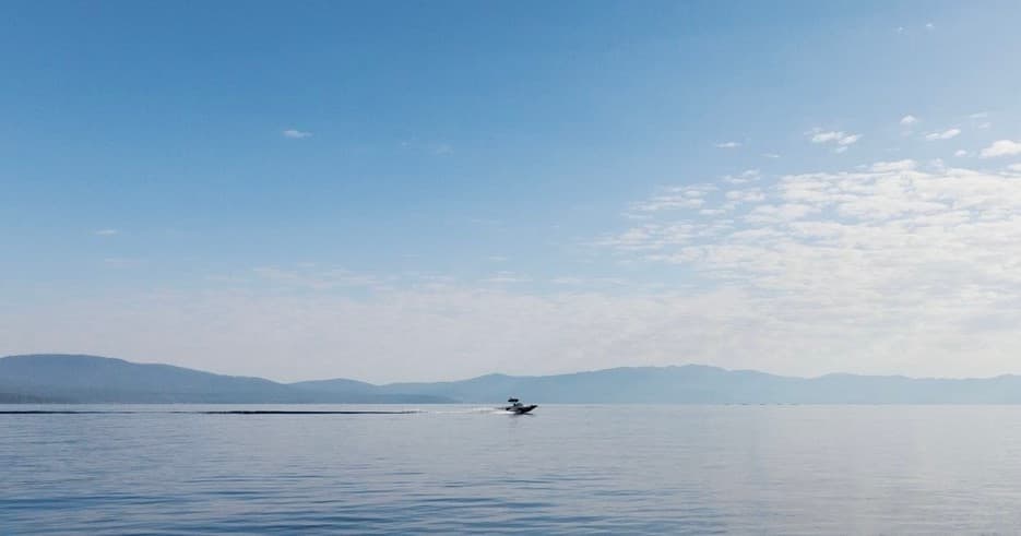 Small boat crossing calm Lake Tahoe with distant mountains
