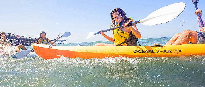 Woman kayaking in bright orange kayak on rippling lake waters