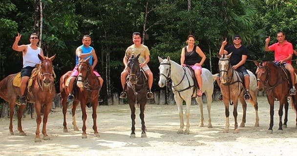 Guided horseback tour with riders on sandy tropical jungle trail