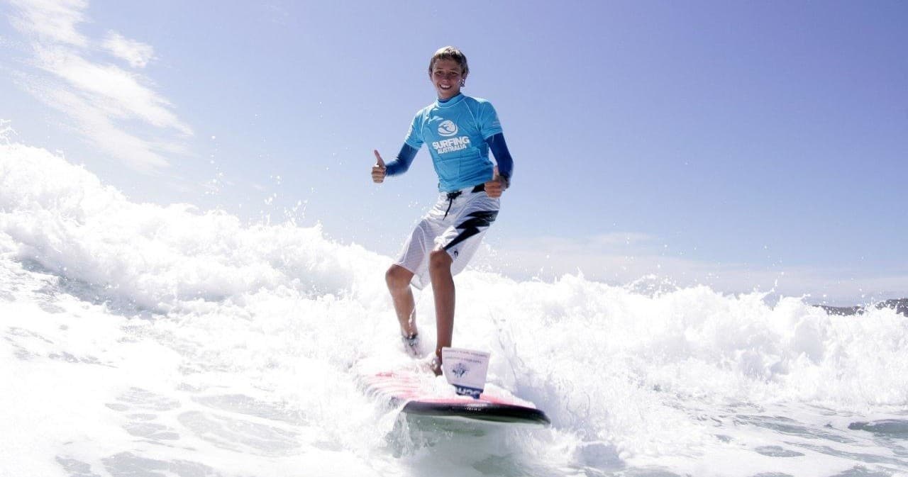 Surfer riding breaking ocean wave at sunny beach competition