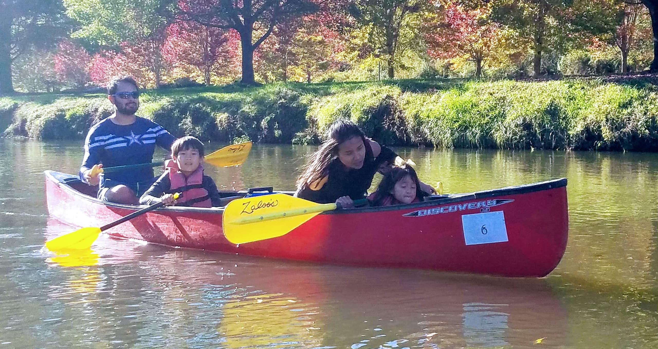 Family canoe paddling on calm river during sunny day outing
