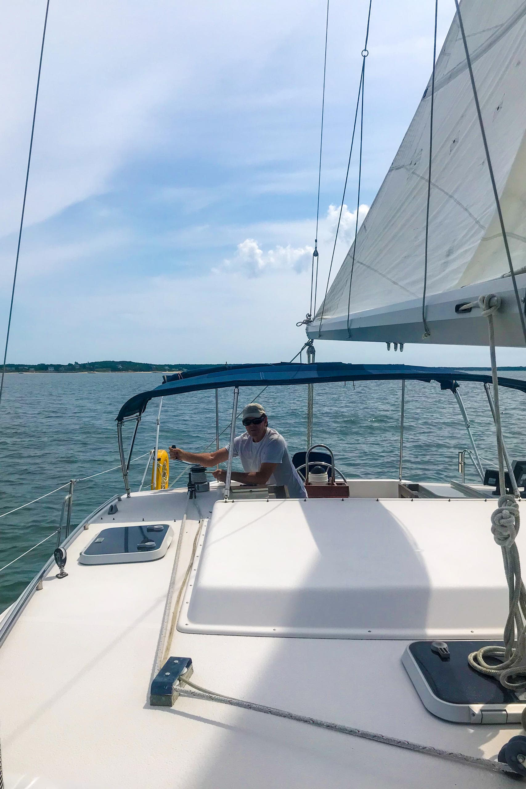 Helmsman steering catamaran under sail in coastal waters