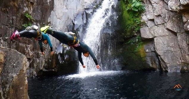 Canyoning jump into waterfall pool amid rocky canyon