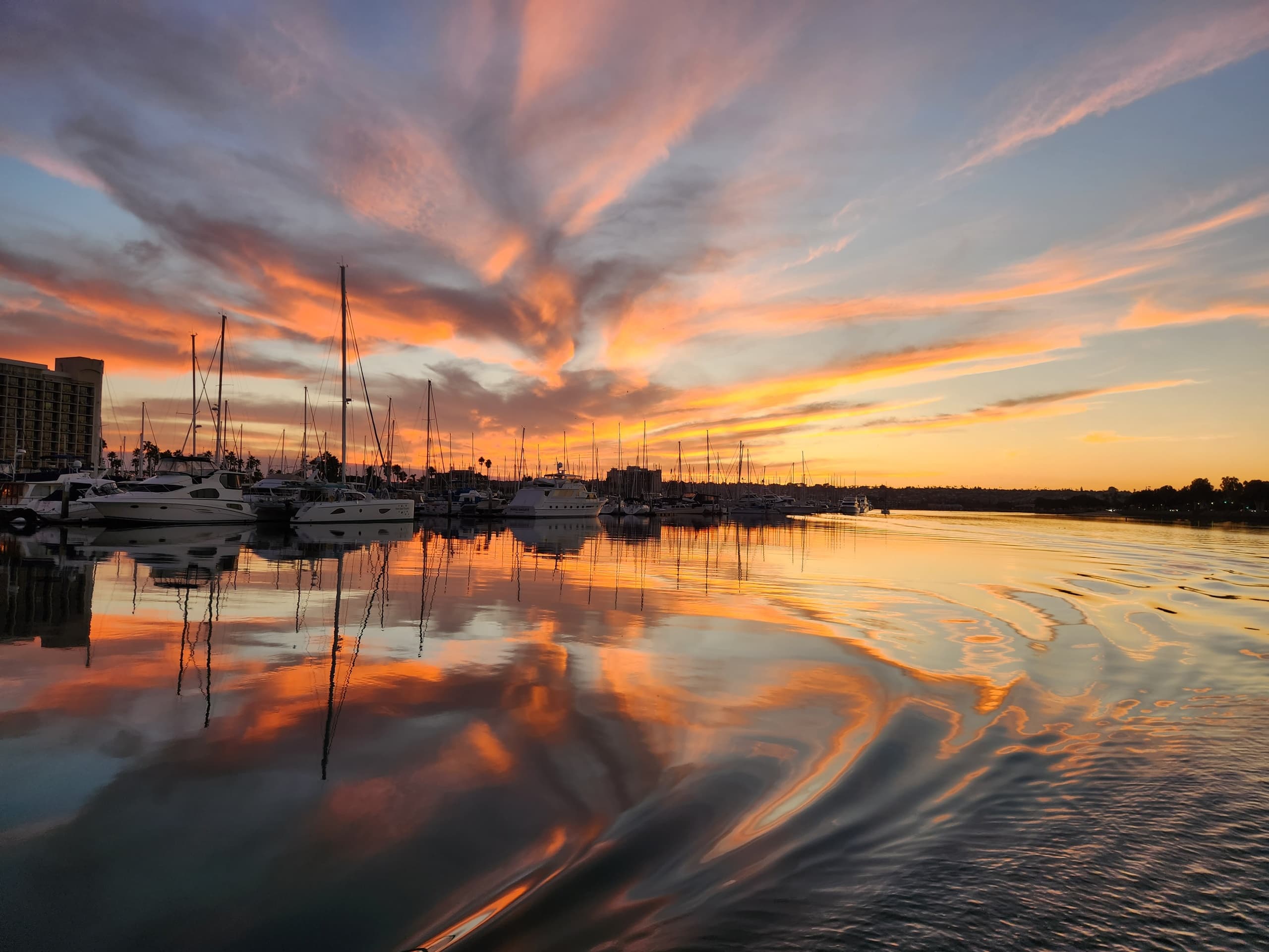 Sunset marina with sailboats reflecting over calm harbor