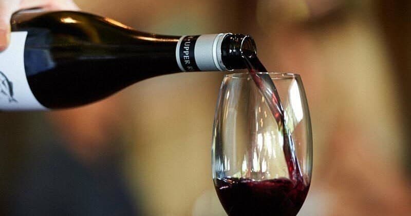Red wine being poured into glass at a tasting event