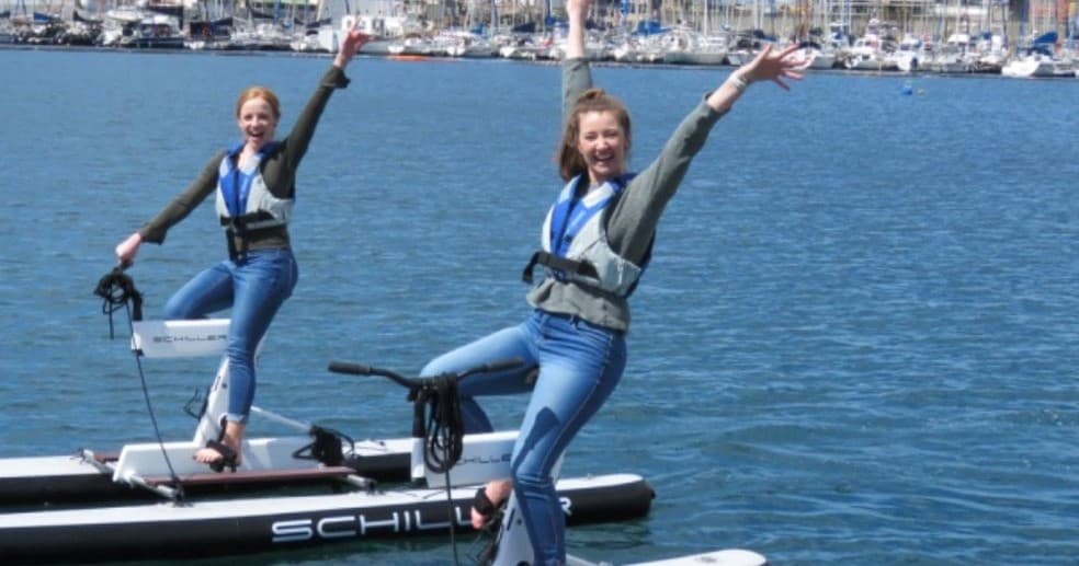Two riders posing on electric hydrofoil boards in marina waters