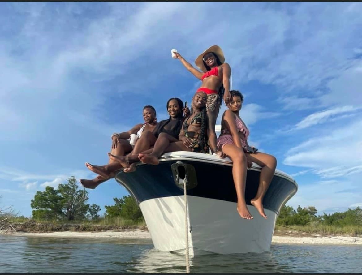 Friends posing on boat bow near tropical shoreline under sky