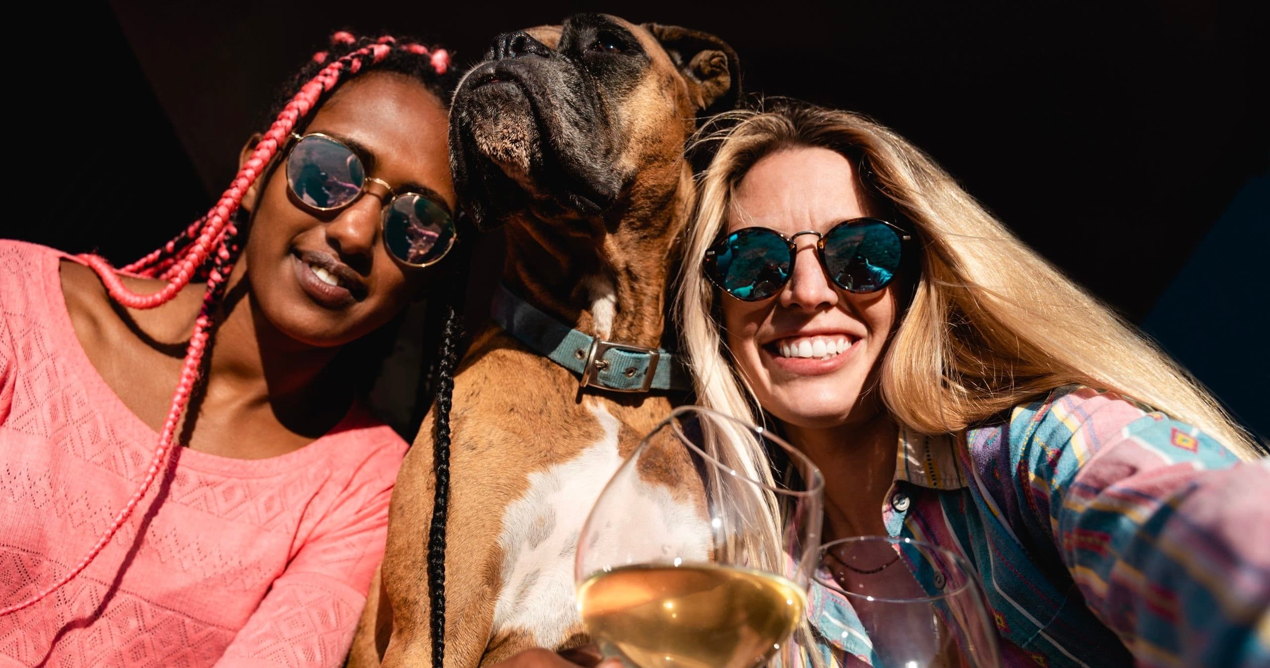 Two friends with dog enjoying outdoor wine tasting selfie