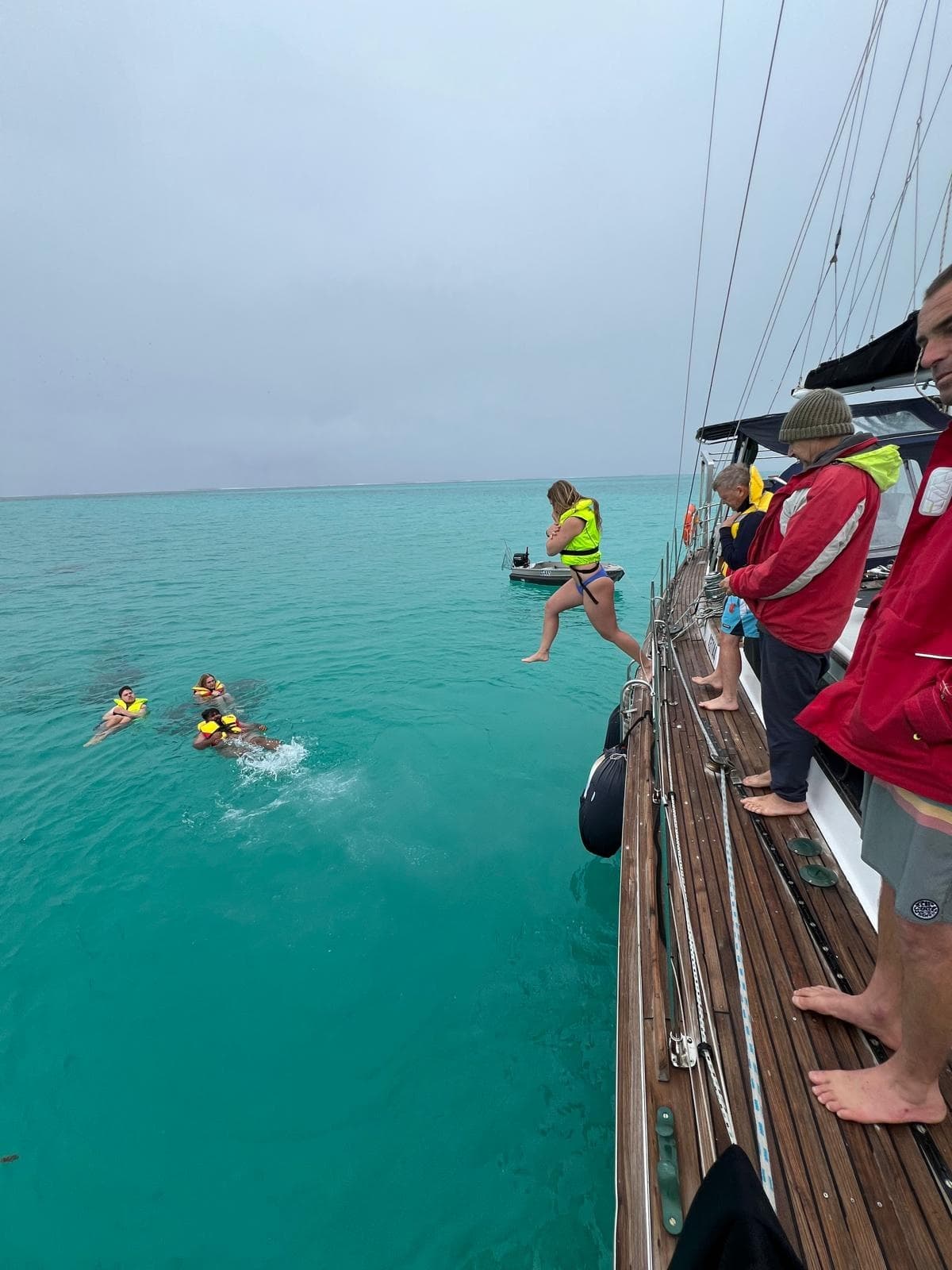 Sail trip passengers jumping into clear turquoise sea from deck