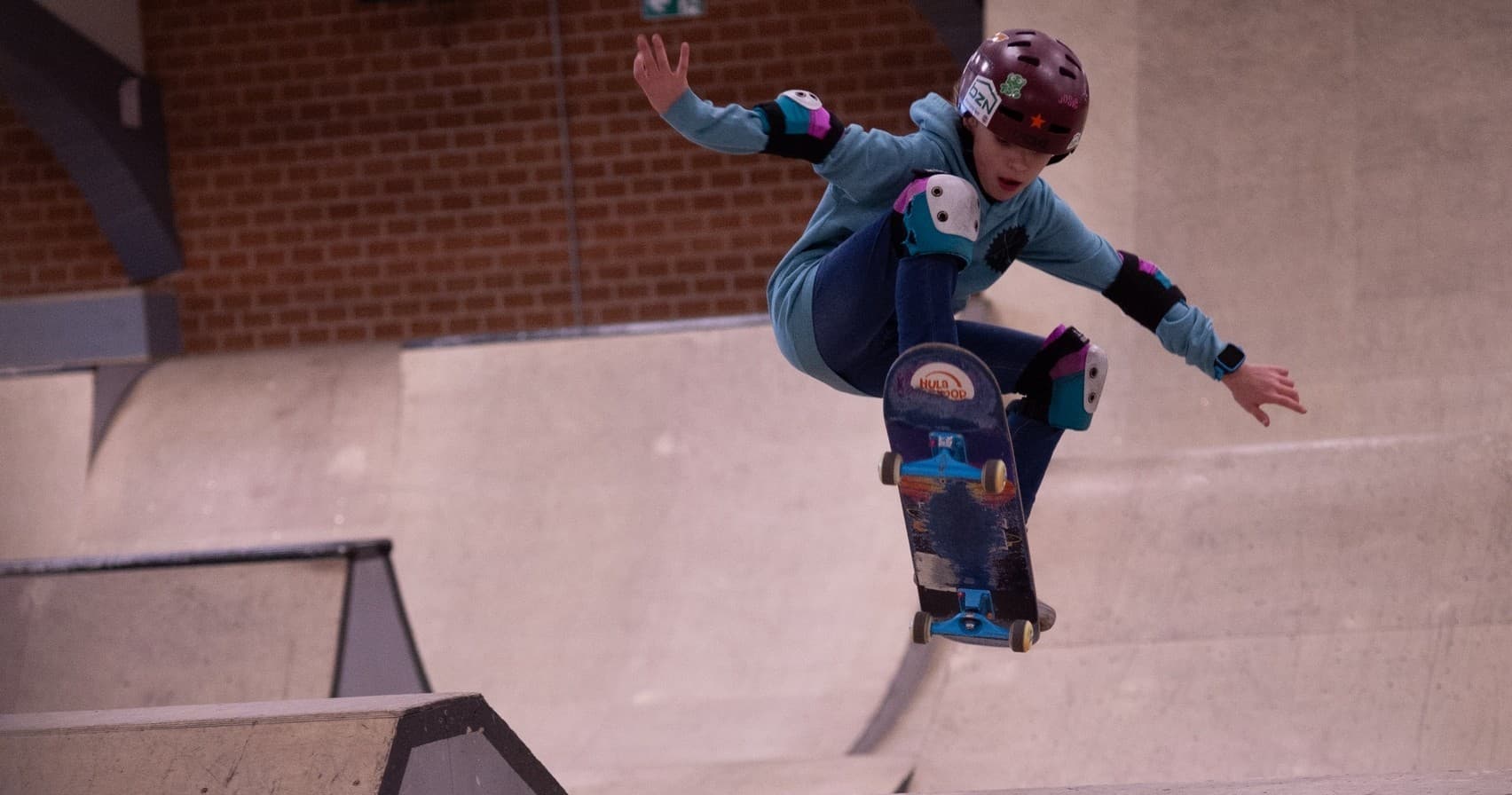 Skateboarder mid-air aerial trick above ramp in indoor Oldenburg skatepark