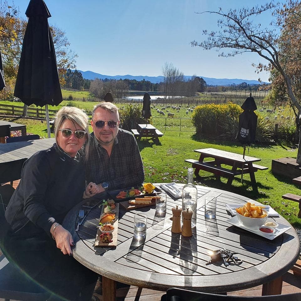 Couple dining outdoors with vineyard view and distant mountains