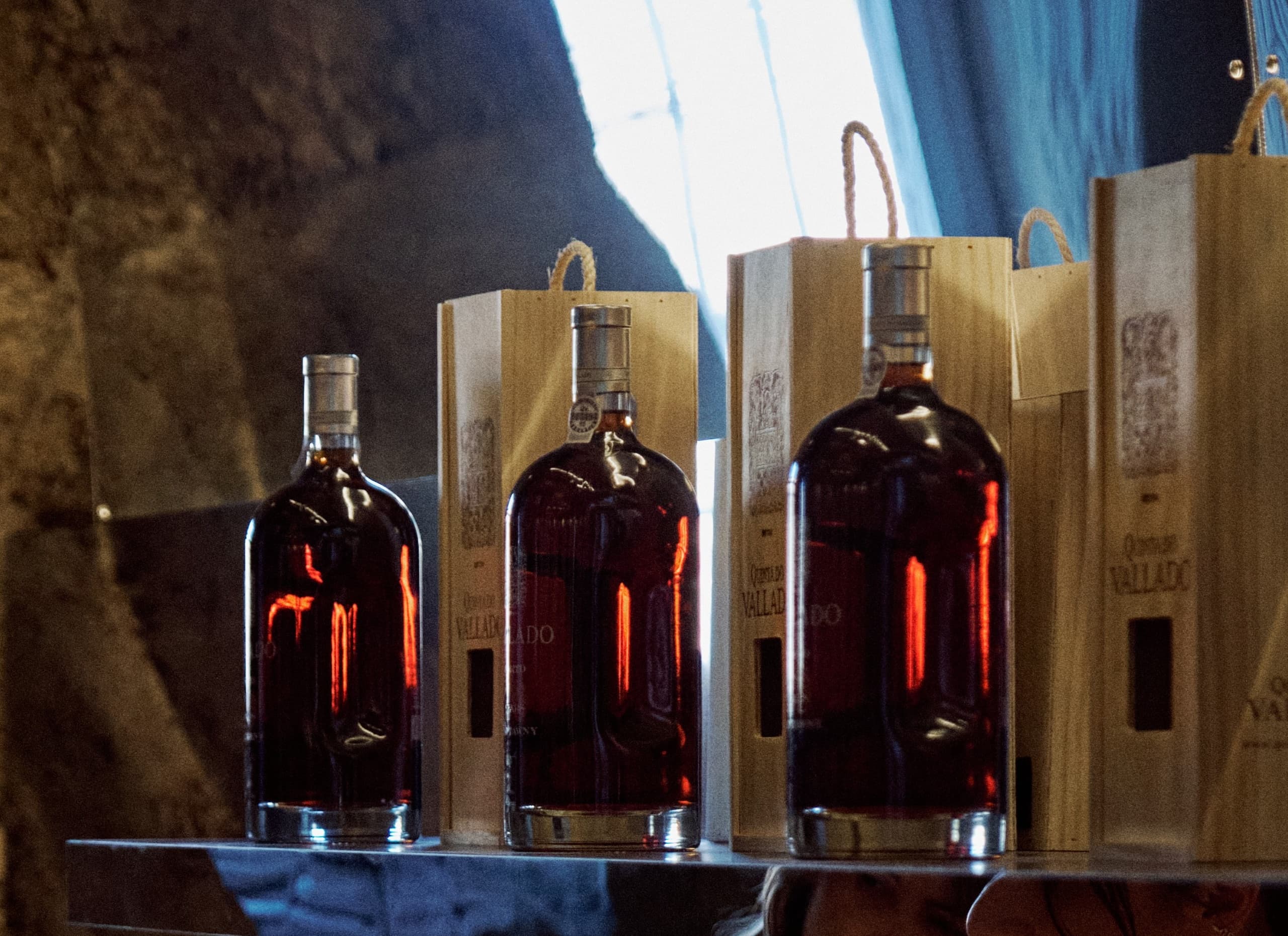 Aged spirit bottles displayed with wooden crates in indoor cellar