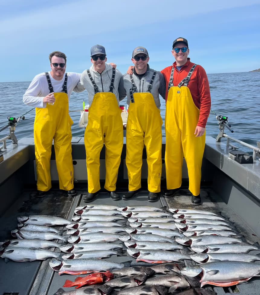 Fishing charter crew with fresh salmon on deck in Sitka waters