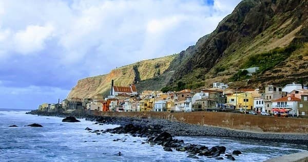 Coastal village by cliffs with rocky shore, Madeira coastline