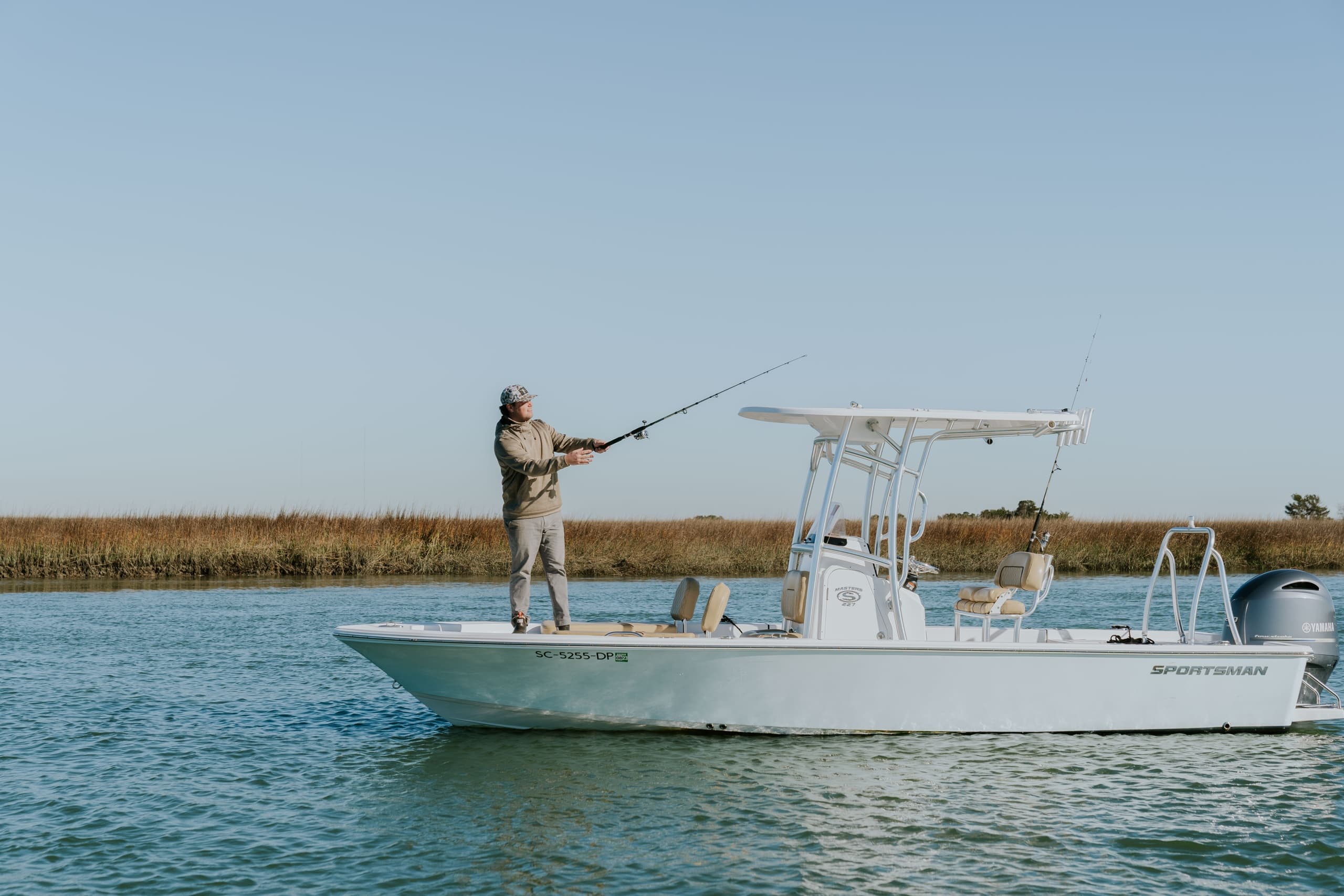 Angler fishing from shallow bay boat against marsh horizon