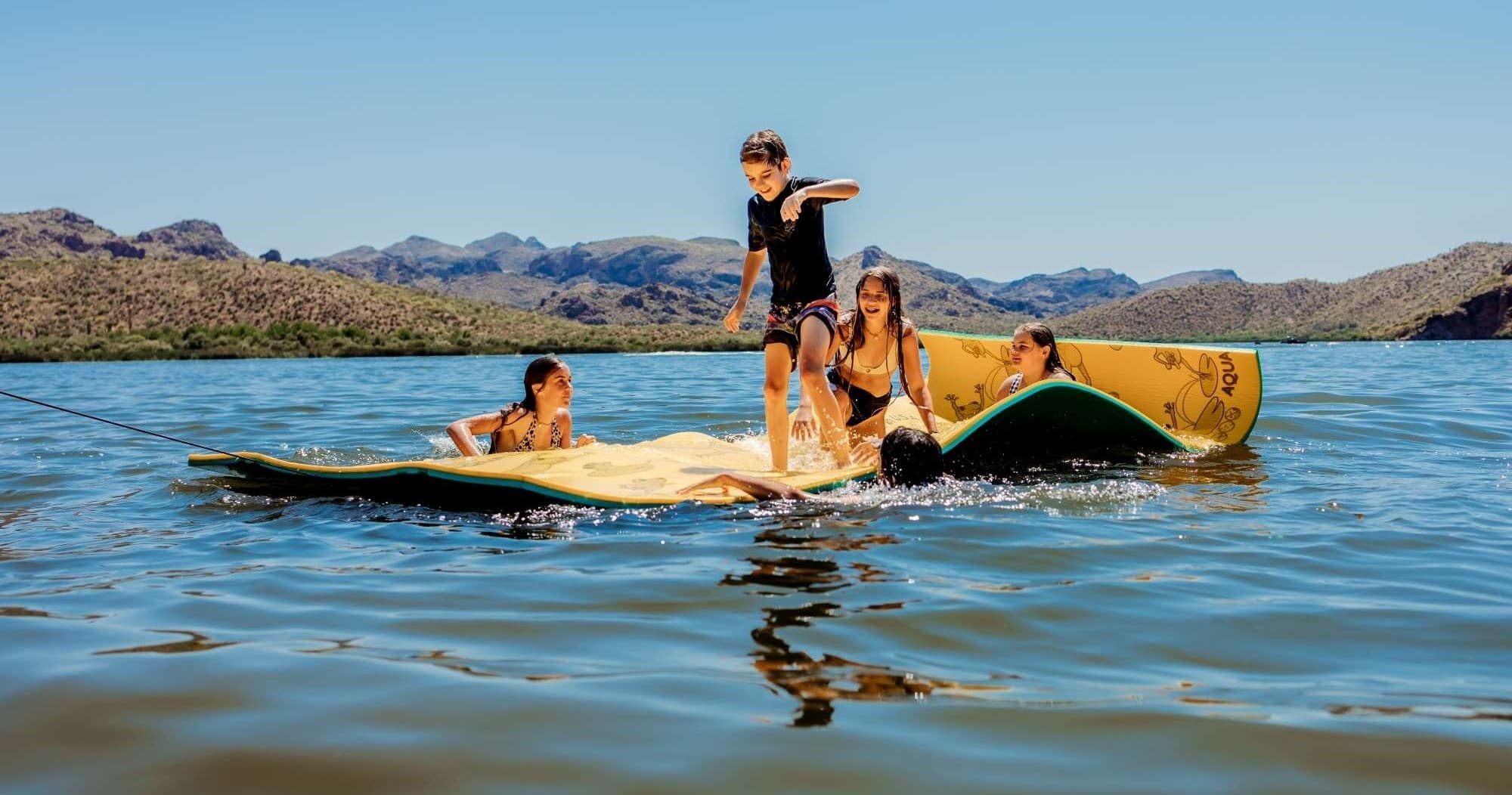 Group paddling and lounging on a large paddleboard on lake