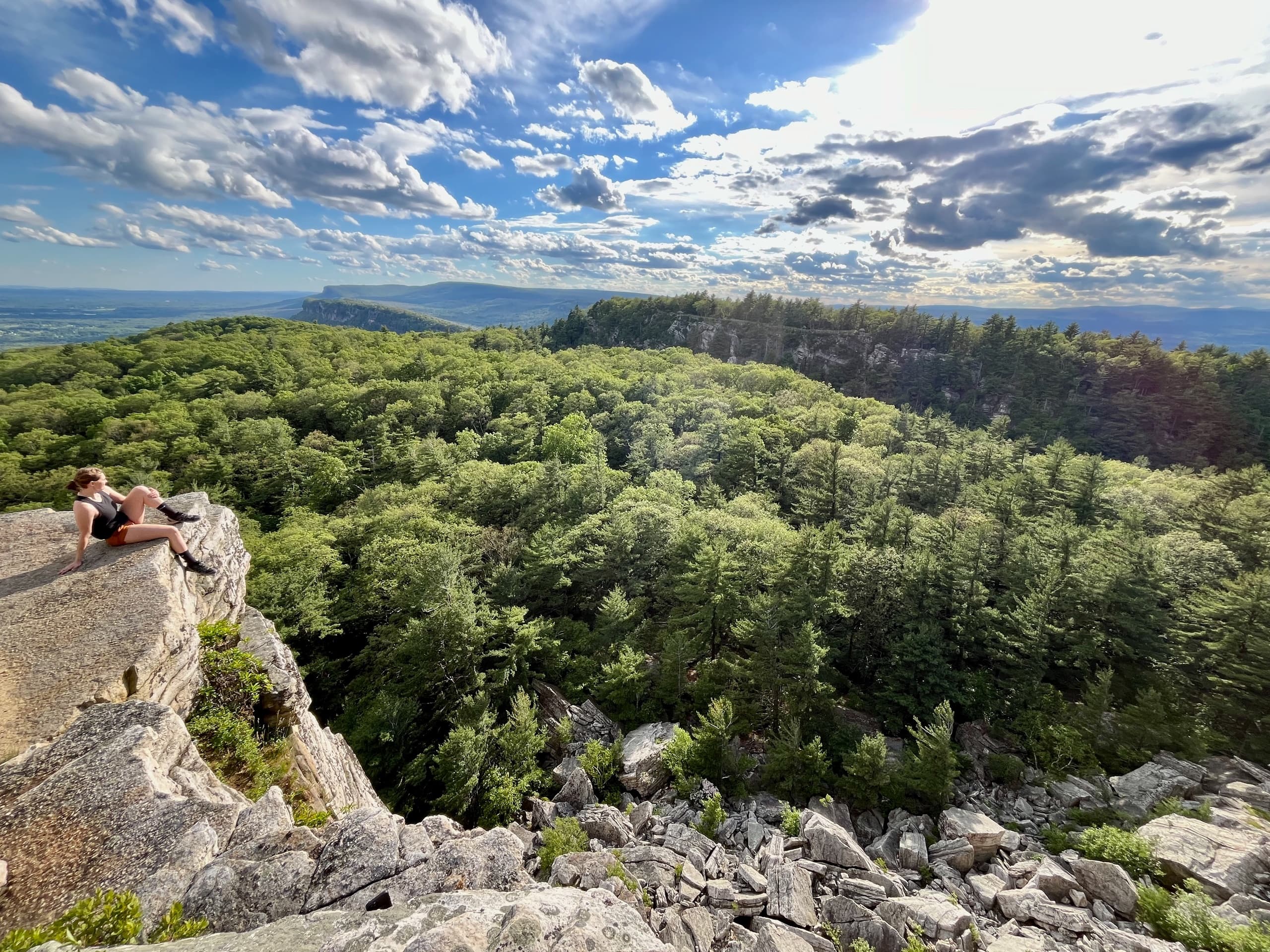 Hiker lounging on cliff overlooking expansive forested vista