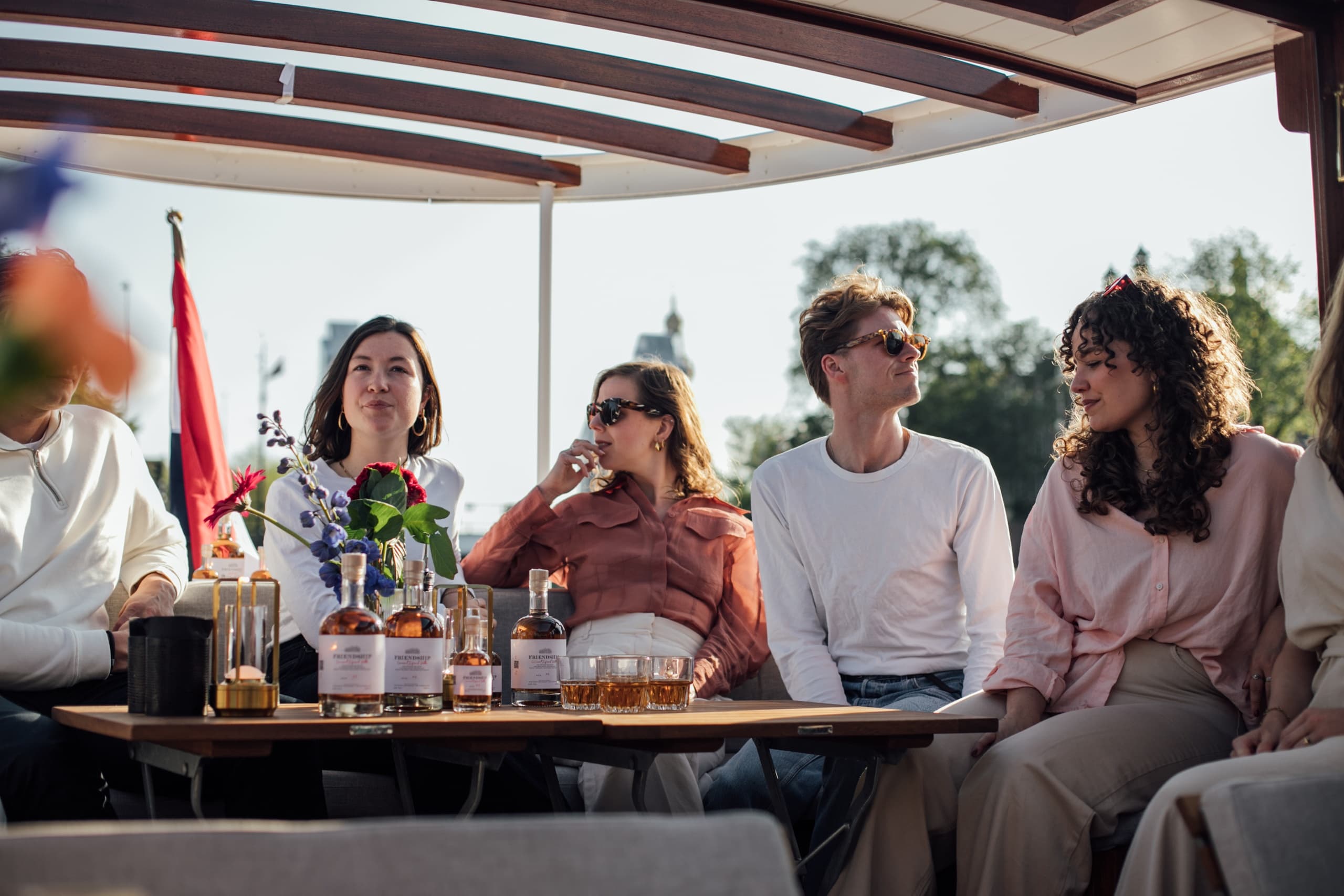 Group socializing on covered Amsterdam canal boat during cruise