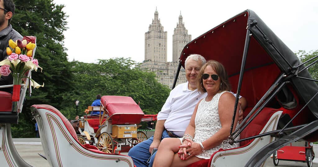 Couple enjoying Central Park carriage ride with skyline