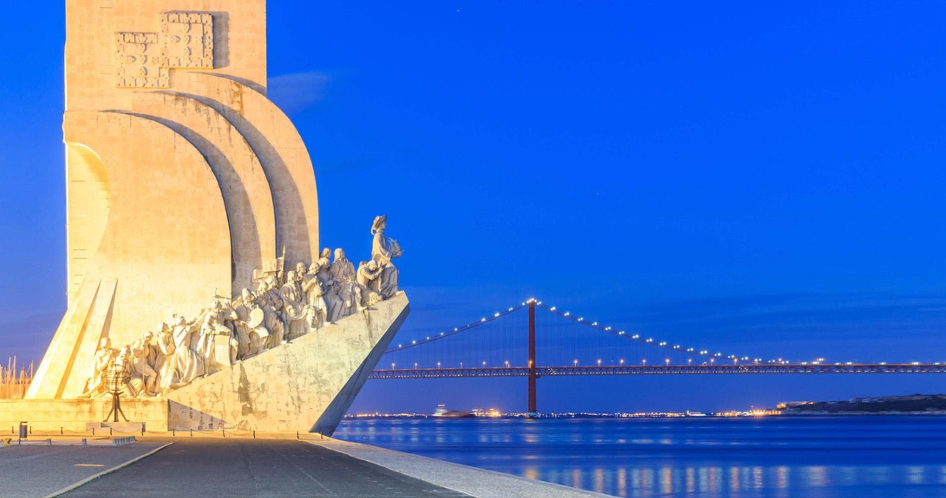 Monument at Lisbon waterfront with bridge across Tagus River