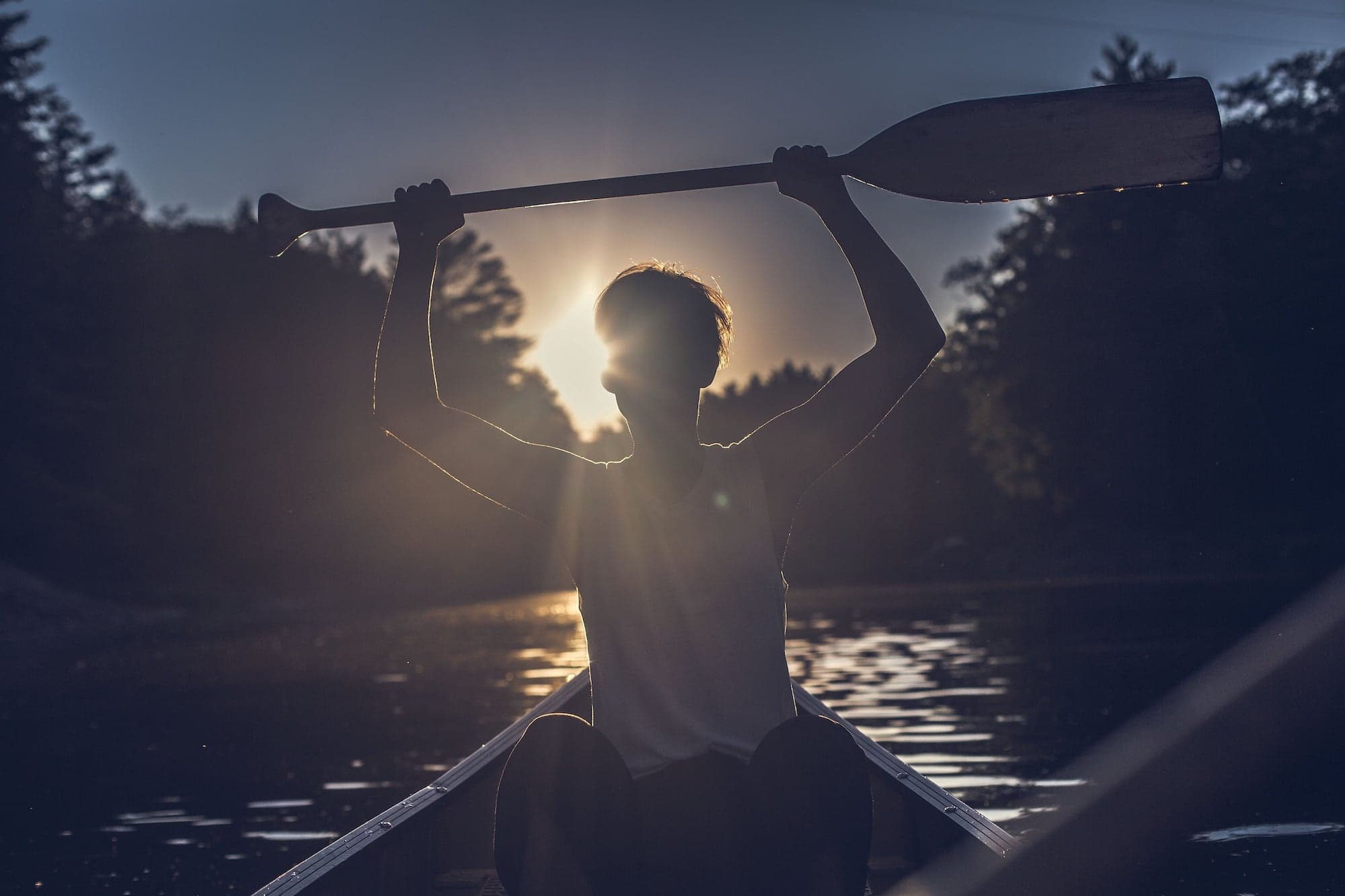Sunset canoe silhouette with paddler on tranquil river