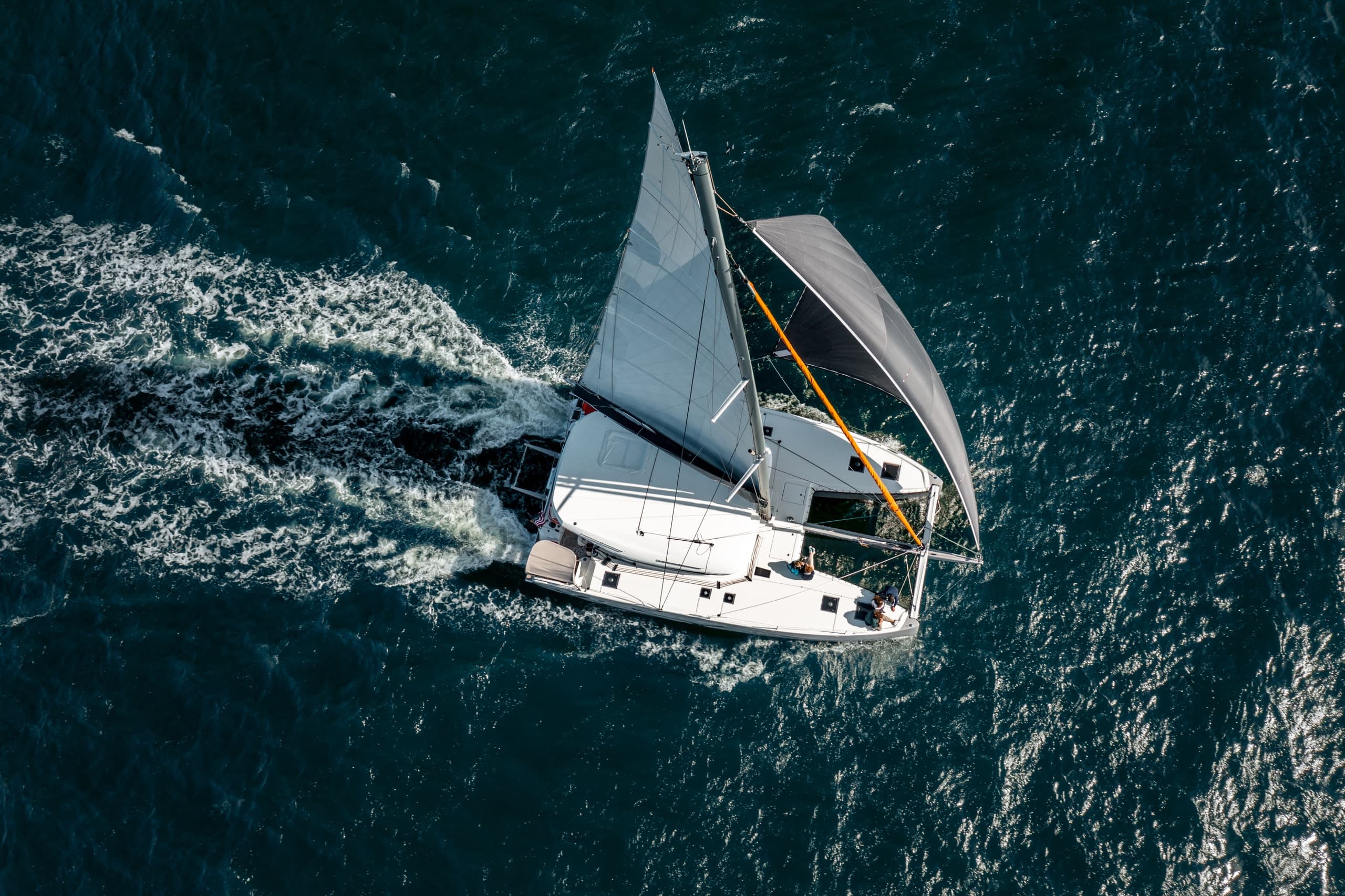 Aerial view of a sailing catamaran cutting through choppy sea