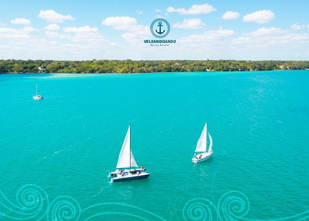 Two sailboats drifting on vivid turquoise lagoon near coast