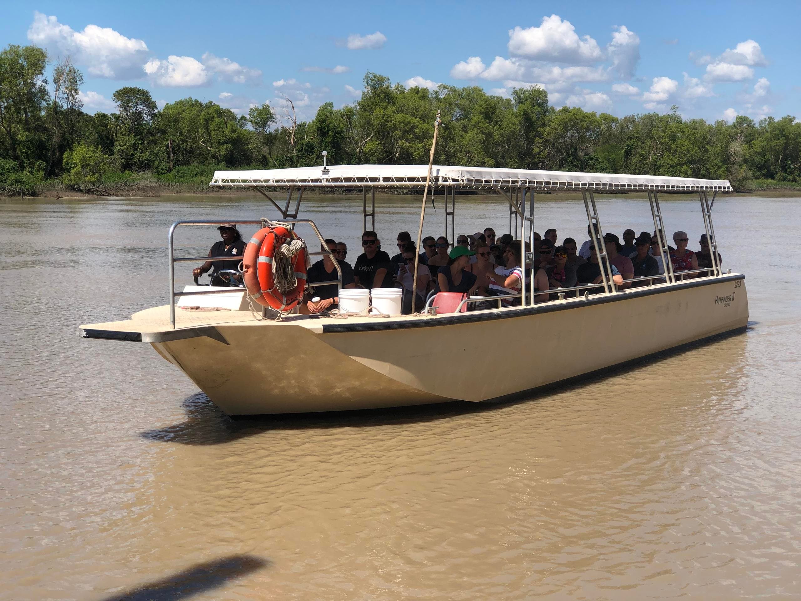 Tour group cruising on shallow muddy river in mangrove wetlands