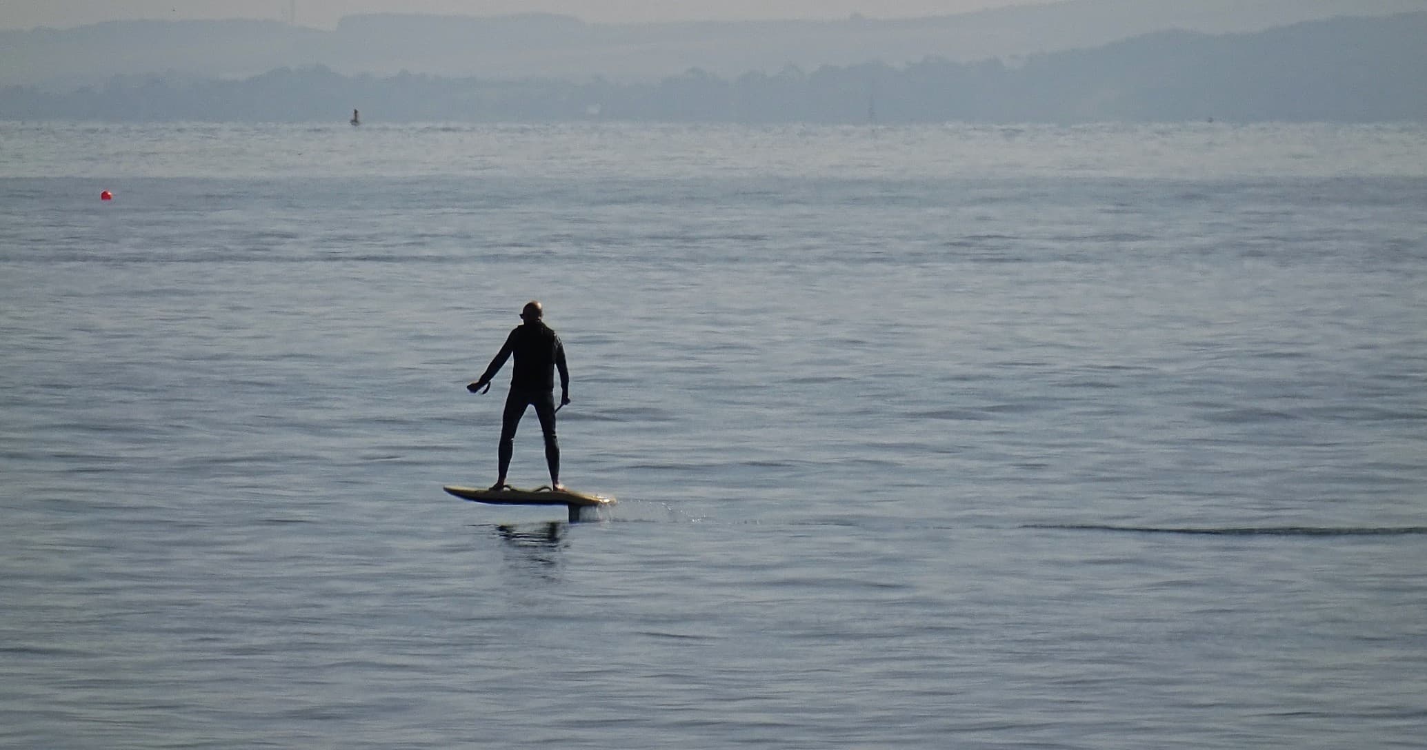 Standup paddleboarder cruising calm sea at open horizon