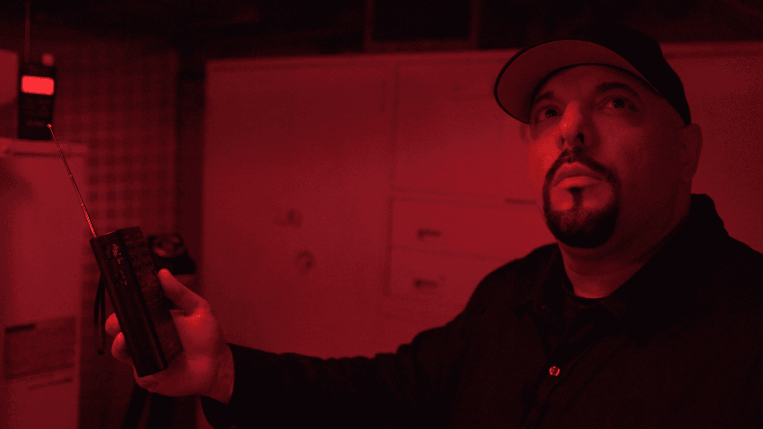 Paranormal investigator scanning basement with EMF meter in red light