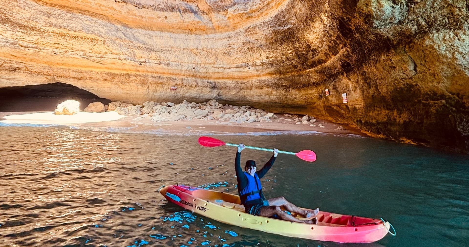 Solo kayaker paddling into Benagil sea cave, Algarve coastal tour