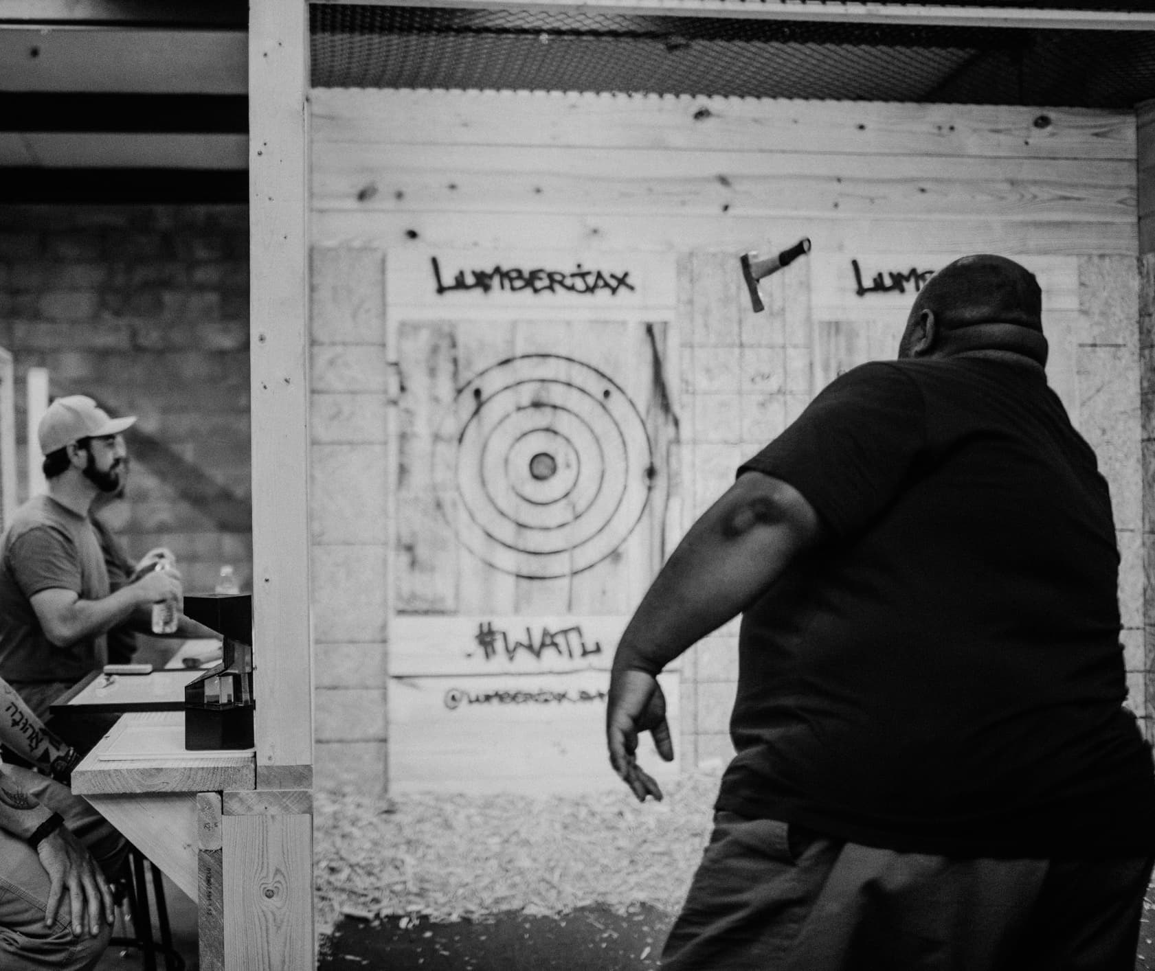 Axe thrower mid-throw at indoor lane with bullseye target