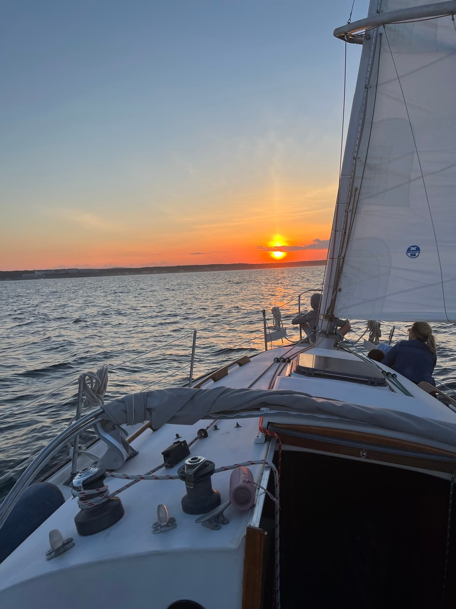 Sailing cruise at sunset on open water, passengers relaxing on deck
