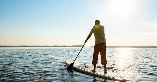 Stand-up paddleboarding at sunrise on calm ocean near Long Beach