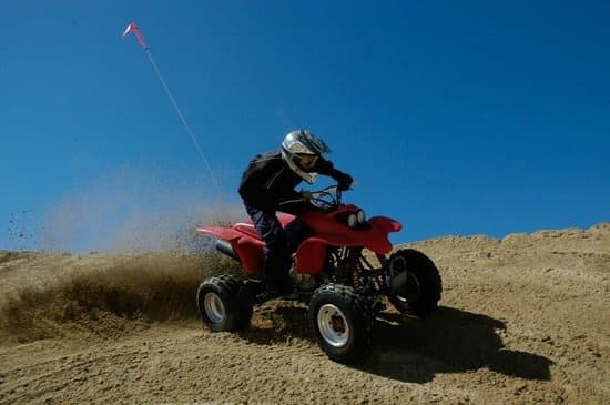 ATV rider kicking up sand in a high-speed off-road dune run
