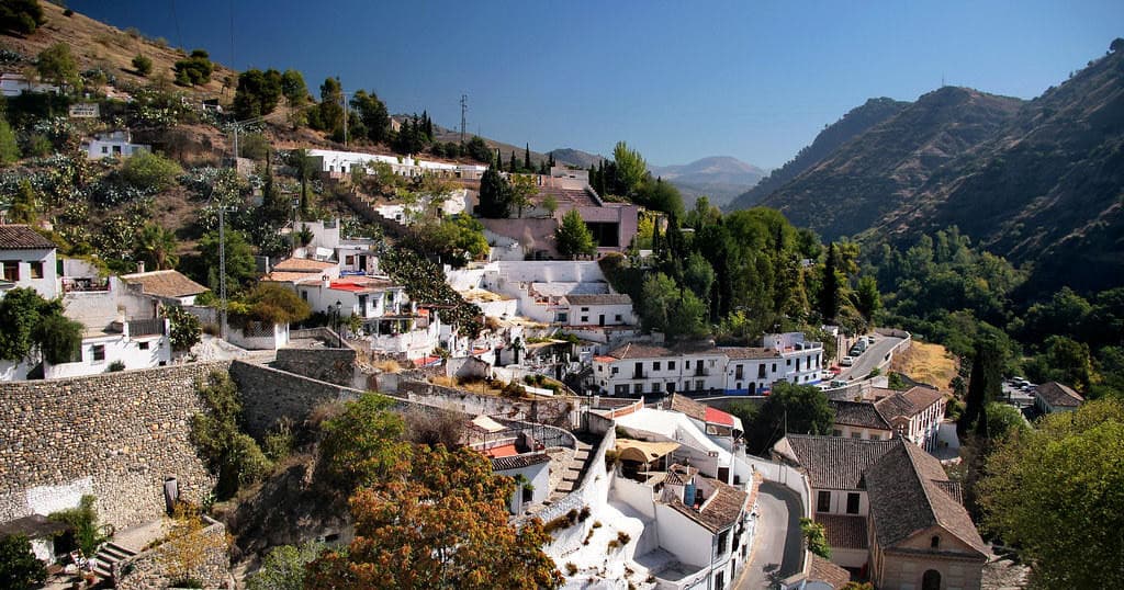 Hikers exploring white hillside village with mountain views, Granada
