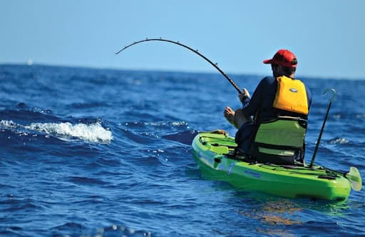 Angler kayak fishing on open ocean waters, person casting line