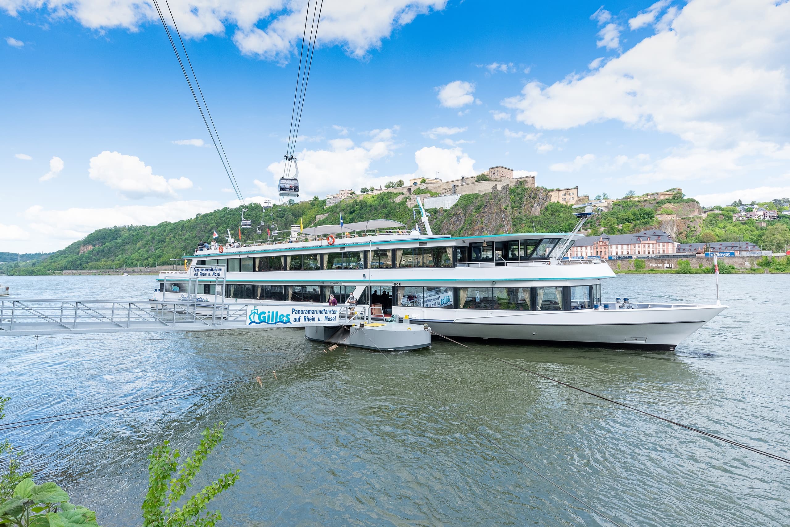 Passenger ferry docking under cable car lines on scenic river