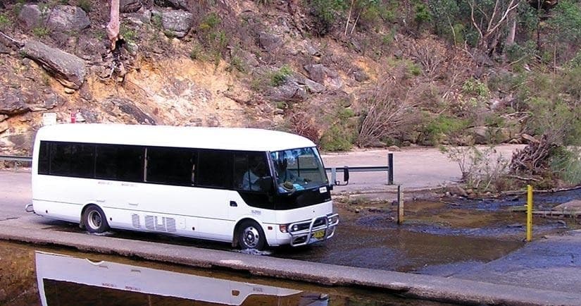 Tour coach parked at trailhead near rugged bushland access point